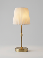 Gold cordless table lamp with pleated cream shade on a console table