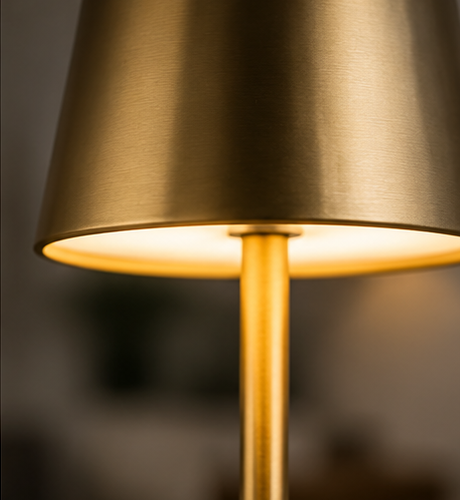 Close-up of the gold Cotswold cordless lamp tapered shade and warm glow