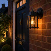 Dulwich outdoor wall light glowing on brick beside a navy front door at dusk