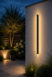 Ealing linear outdoor wall light on a garden wall at blue hour with landscaped planting