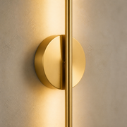 Close-up of the Elowen gold linear wall light and circular mounting plate
