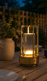 Gold Grosvenor cordless lamp lit on an outdoor dining table at dusk