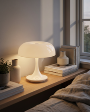 White cordless table lamp glowing on a shelf beside books