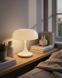 White cordless table lamp glowing on a shelf beside books