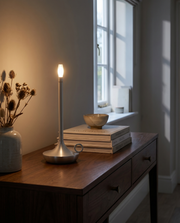 Silver cordless table lamp glowing on a hallway console table