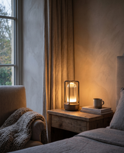 Black metal cordless table lamp glowing on a bedside table