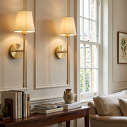 Pair of brass wall lights mounted either side of a console table, warm glow