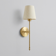 Gold brass wall light with cream fabric shade on plain background