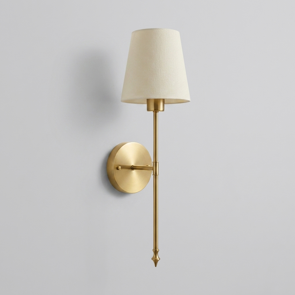 Gold brass wall light with cream fabric shade on plain background