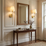 Pair of brass wall lights either side of a mirror in a hallway, warm glow