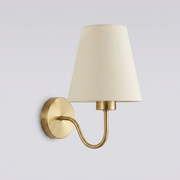 Gold brass wall light with cream fabric shade on plain background