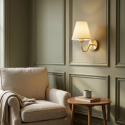 Brass wall light beside a reading armchair in a living room corner, warm glow