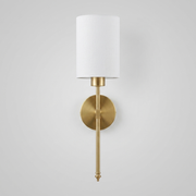 Gold brass wall light with white fabric shade on plain background