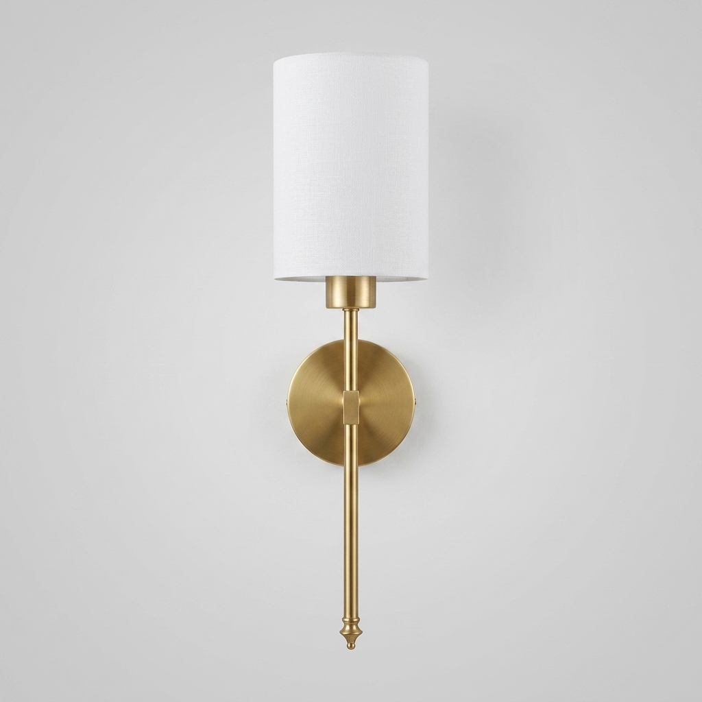 Gold brass wall light with white fabric shade on plain background