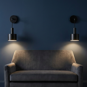 Pair of black wall lights beside a sofa in a calm living room, warm glow