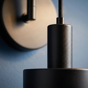 Close-up of backplate and cylindrical shade detail on black wall light
