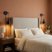 Pair of black wall lights either side of a bed headboard, warm bedroom glow