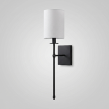 Black candlestick-style wall light with white fabric shade on plain background
