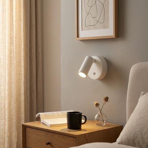 White pivoting wall light above a bedside table, warm reading glow