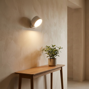 Round magnetic wall light glowing above a hallway console table