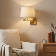 Gold swing-arm wall light beside a reading armchair