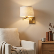 Gold swing-arm wall light beside a reading armchair