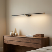 Black and brass linear wall light above a bedroom dresser