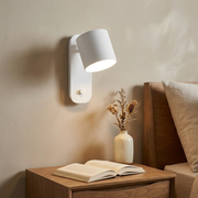 White rotatable cone wall light above a bedside table