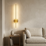 Gold linear wall light glowing beside a living room side table