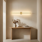 Long linear wall light glowing above a hallway console table
