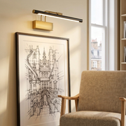 Brass and black picture-style wall light above framed artwork