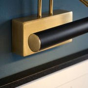 Close-up of brass mount and black bar of picture-style wall light