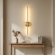 Gold vertical linear wall light above a hallway console table