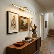Gold battery wall light glowing above a hallway console table