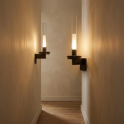 Black battery wall light glowing warmly in a hallway