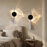 Dual-light battery wall light glowing warmly beside a bed