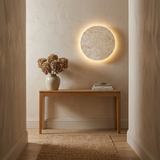 Round travertine wireless wall sconce glowing on a bedroom feature wall