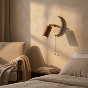 Rotatable travertine wall light in Walnut finish glowing on a bedroom feature wall