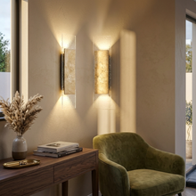 Travertine wall light glowing on a hallway feature wall