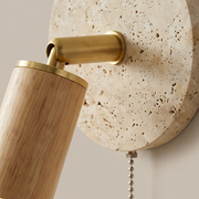 Close-up of brass trim ring and pull-chain switch on a Primrose rotatable travertine wall light