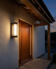 Black rectangular outdoor wall light beside a front door with warm evening glow