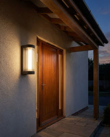 Black rectangular outdoor wall light beside a front door with warm evening glow