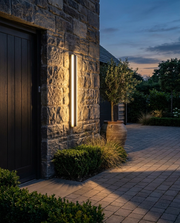 Black linear LED outdoor wall light beside a driveway entrance at dusk