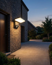 Solar wall light with sensor lighting a side entrance and driveway at dusk