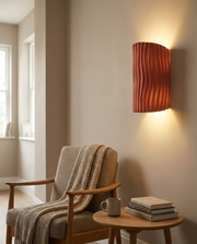 Red wavy resin wall light casting a warm glow beside a living room armchair