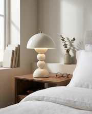 White cordless table lamp with stacked dome shade on a bedside table