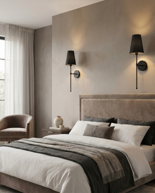 Black battery wall light pair beside a bed creating warm symmetrical bedside light