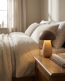 Wood mushroom cordless table lamp glowing on a bedside table