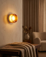 Lumiere Glass Wireless Wall Sconce glowing warm amber in a styled living room