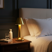 Mila Cordless Table Lamp - Gold, glowing on a bedside table
